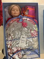 Maplelea Girl doll boxed with clothing and accessories visible under plastic cover.