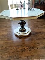 Front view of vintage 1970s octagonal Formica dining table with decorative gold edging and a dark pedestal base with gold trim on hardwood floor.