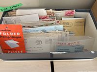 Box containing an assortment of WWII-era letters and envelopes arranged upright with a stamp hinge booklet visible in the box.