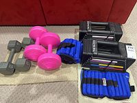 Overview of entire lot showing adjustable dumbbell blocks, vinyl and hex dumbbells, and blue weight straps