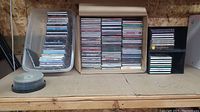 Photo showing multiple stacks of music CDs and a stack of blank recordable CDs on a shelf