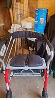 Adjustable Evolution walker with padded seat and back cushion visible, along with white forearm crutches and boxed toilet support rail in background