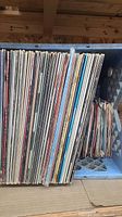 Photo showing a box with approximately 50 LP records stacked vertically, with sleeves visible.