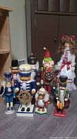 Full group photo displaying all 8 nutcrackers arranged on floor including the Pier 1 Imports girl nutcracker