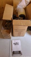 Paint Zoom painting system components still in original cardboard boxes with instruction manual beside them.
