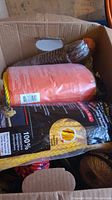 Box containing several spools of rope including a red and yellow packaged rope and coiled ropes of different colors and sizes