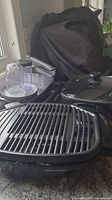 Photo showing Hamilton Beach electric grill with ridged cooking surface and glass lid, along with other kitchen accessories.