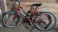 Full side view of red SuperCycle mountain bike with nubby tires, black seat, and grip shifters.