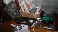 Photo showing box with cookie cutters, vintage Proctor-Silex Super Shooter with metal slicing components, various baking pans including pie plates and loaf pans, commercial size baking sheet behind