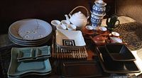 Overview photo of Asian style tea pots, cups, stoneware plates, and sushi serving trays arranged on a table