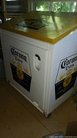 Side view showing white metal cooler with Corona Extra logo and handle