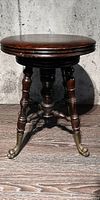 Front angled view showing the round wooden seat, turned wood legs, and brass dragon head feet.