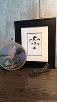 Photo showing framed print, hand drum, and small metal sculpture together