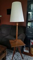 Full view of mid-century modern floor lamp with large natural flared drum shade, teak post, and square tabletop with three supporting legs.