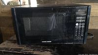 Front view of the Black and Decker small microwave showing the door with glass window and the Black and Decker logo.