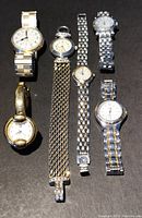 Six vintage watches arranged on a dark surface showing their faces and bands clearly to identify brand and style.
