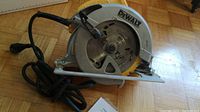 Wide shot of DeWalt circular saw with attached power cord on wooden floor.