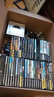 Top-down view of box containing silver GameCube console, controllers, cables and stacked game cases