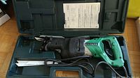 Full view of Hitachi reciprocating saw inside original green hard plastic carrying case with manual and blades included.