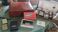 Leather-like personal care case items including two Zippo lighters in original boxes, and vintage opera glasses box