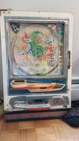 Front view of the pachinko machine showing the playfield and colorful internal artwork.