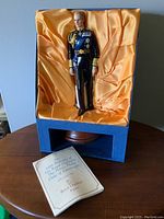 The Duke of Edinburgh Royal Doulton figurine displayed in open presentation box with satin lining and COA booklet on table.