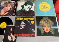 Top side view showing 6 album covers including Madonna Angel, Terence Trent D'Arby, Dean Martin, Johnny Cash, Bonnie Tyler, and another album along with a vinyl record and a booklet.