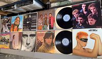 12 assorted vinyl record albums laid out, showing a variety of album covers and two records removed from sleeves.