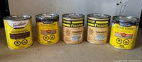 Five cans of wood stain by Varathane, Minwax, and Torcan placed side by side showing front labels