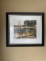 Full view of the framed print "The Canoe" by Tom Thompson showing the canoe near water and trees, with a dark frame and white matting.