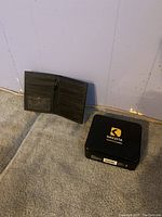 Wallet open showing card slots and ID window inside alongside the Dakota branded tin box closed.