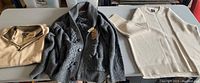 Three sweaters laid out on a table: grey knit cardigan, beige quarter zip, and cream sweater