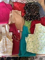 Overview photo showing a variety of sleeveless tops in different colors and materials, including textured, printed, and solid styles.