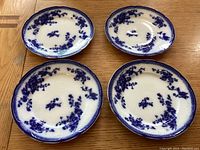 Four antique Grindley Flow Blue plates displayed showing the blue floral pattern and scalloped edges.