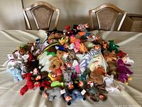 Front view of 60+ vintage Teenie Beanie Babies plush toys displayed on table with original TY tags.