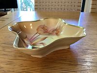 Side angled view of the antique bowl showing the floral painting and shape.