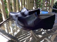 Side view of the black leather slip-on shoes showing overall design and shape.