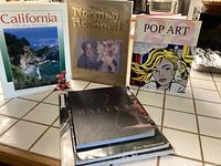 Photo showing five hardcover books with artistic covers: California On My Mind, Norman Rockwell, Pop Art, Dali Ballet, and one unidentified by Paul Morrison along with 180 Magazine.