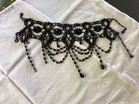 Photo showing jet black crystal choker necklace with lace-like design and hanging bead strands