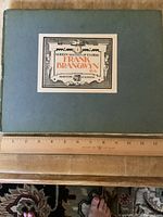 Blue hardcover book with printed title label 'Modern Masters of Etching Frank Brangwyn R.A. 44 Leicester Sq London',' ruler showing size approx 12 inches wide