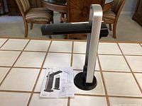Mobile OttLite LED lamp standing upright on table next to its instruction manual.