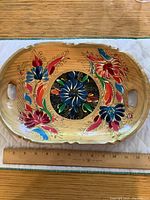 Top view of wooden tray showing colorful hand painted floral folk art design with central black circular pattern and cutout handles.