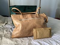 Front view of vintage ostrich leather handbag with matching wallet placed side by side on a bed surface