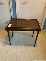 View of the full butler's table with lacquer finish, raised edges, and metal handles on sides.