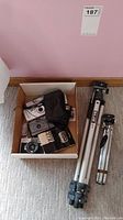 Box with 5 cameras, carrying case and 2 tripods seen