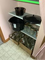 Full lot view showing two boxes of glass jars on floor, black speckled enamel canner with lid and metal rack on shelves.