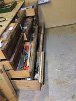 Wide view of multiple open wooden drawers along wall showing variety of hardware and supplies organized in compartments and bags.