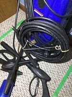 Close-up of two black spray wands and coiled hose, showing their condition and connectors.