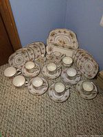 Full set of Royal Albert Petit Point china showing snack plates, cups, cream and sugar, salt and pepper, and serving plates arranged on carpet