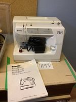 Full view of the Kenmore sewing machine model 385 along with instruction manual and spool of thread on table.